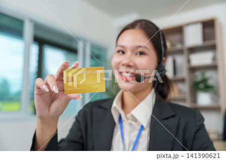 Asian customer service representative holding credit card for online payment support Asian customer service representative holding credit card for online payment support 141390621