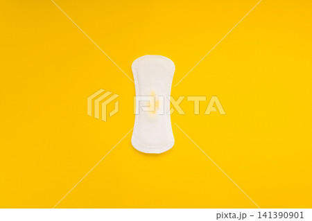 Sanitary Pad with Small Yellow Urine Stain on Yellow Background Sanitary Pad with Small Yellow Urine Stain on Yellow Background 141390901