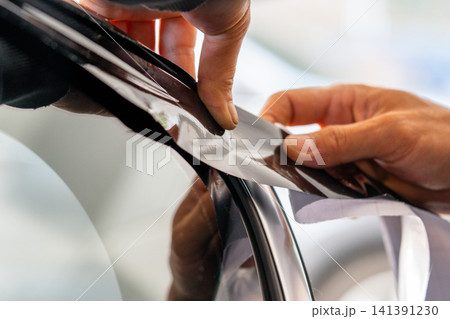 A car wrapping specialist applies a polyurethane film to the car. Detailer PPF A car wrapping specialist applies a polyurethane film to the car. Detailer PPF 141391230