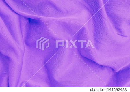 Horizontal close up overhead view of a crumpled purple cotton fabric texture with soft waves and elegant folds creating a smooth textile background design Horizontal close up overhead view of a crumpled purple cotton fabric texture with soft waves and elegant folds creating a smooth textile background design 141392488