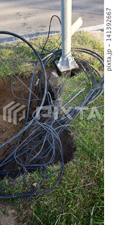 Cable wires tangled near a utility pole in a grassy area by a road Cable wires tangled near a utility pole in a grassy area by a road 141392667