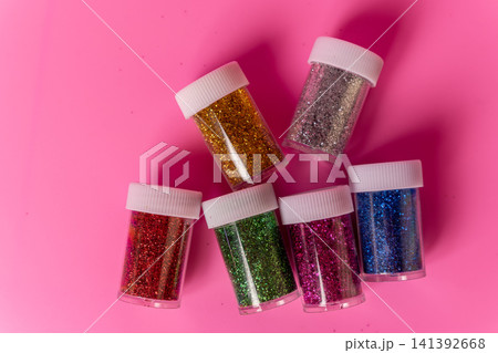 Containers of sparkles for crafts on a pink surface Containers of sparkles for crafts on a pink surface 141392668