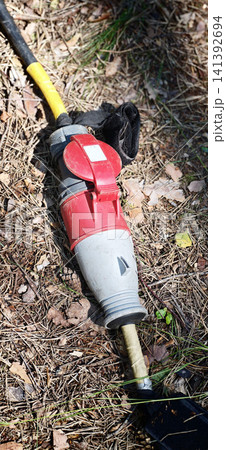 Power tool connector lying on the ground in a wooded area during daytime Power tool connector lying on the ground in a wooded area during daytime 141392694