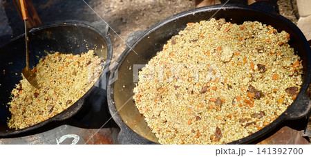 Cooking grains and vegetables in large pots over an outdoor fire 141392700