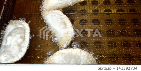 Frying dough items in hot oil in a kitchen at a local market in the morning Frying dough items in hot oil in a kitchen at a local market in the morning 141392734