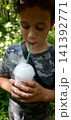Child enjoys a cold drink while standing in a green outdoor area 141392771