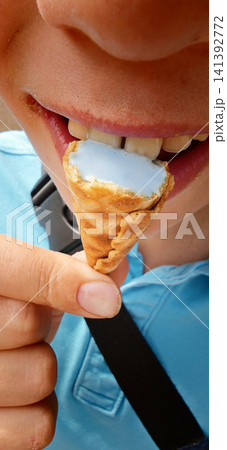 Child enjoys ice cream cone on a sunny day outdoors in the park 141392772