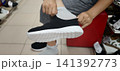 Student tries on shoes in a store while sitting on a red bench 141392773