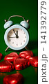 Heart shaped candies and alarm clock on a green surface 141392779