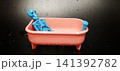 Blue skeleton toy in a pink bathtub with water on a black background 141392782