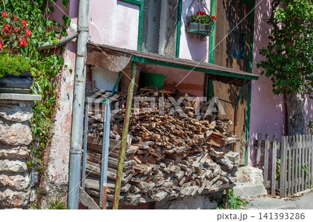 Large Pile of Cut Firewood under a Sheltered Pink Facade in Rustic Alpine village Large Pile of Cut Firewood under a Sheltered Pink Facade in Rustic Alpine village 141393286