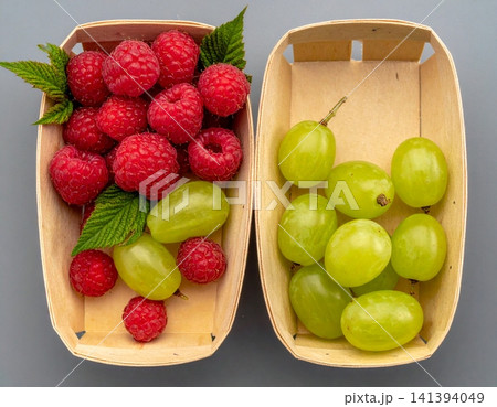 two pulp paper punnets, one filled with fresh red raspbe two pulp paper punnets, one filled with fresh red raspbe 141394049