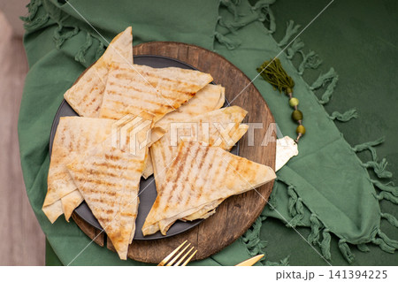 Asian food thin triangular envelopes of dough with filling fried in a pan. Flatbread 141394225