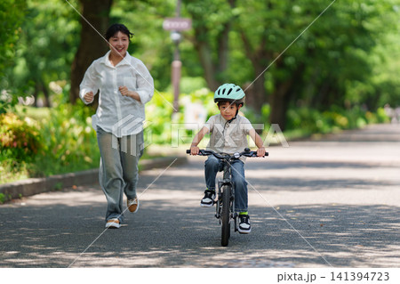 母親と自転車の練習をする小学生の男の子 141394723