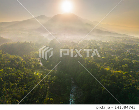 Aerial view of the lush Tegalalang landscape featuring a winding river flowing through dense tropical forest and terraced fields in Indonesia 141394743