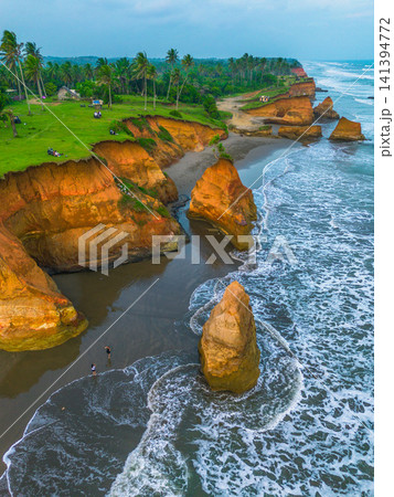 Aerial view of coastal rock formations rising from the sea with crashing waves and sandy beach in Indonesia Aerial view of coastal rock formations rising from the sea with crashing waves and sandy beach in Indonesia 141394772