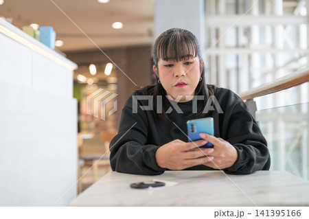 Thai Transgender Woman Using Smartphone at Indoor Cafe Table Thai Transgender Woman Using Smartphone at Indoor Cafe Table 141395166