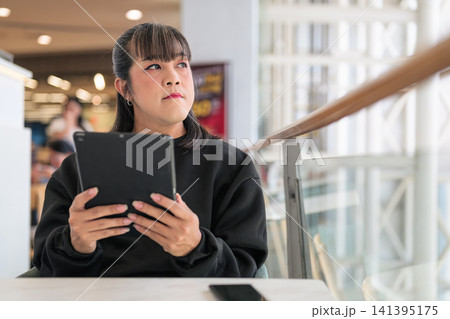 Thai Transgender Woman Holding Tablet at Cafe Table Thai Transgender Woman Holding Tablet at Cafe Table 141395175