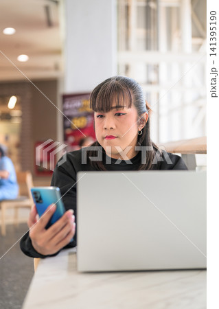 Thai Transgender Woman Checking Smartphone Behind Open Laptop Screen 141395190