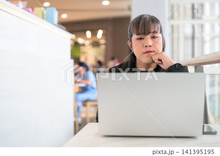 Thai Transgender Woman Resting Chin on Hand Behind Open Laptop Thai Transgender Woman Resting Chin on Hand Behind Open Laptop 141395195