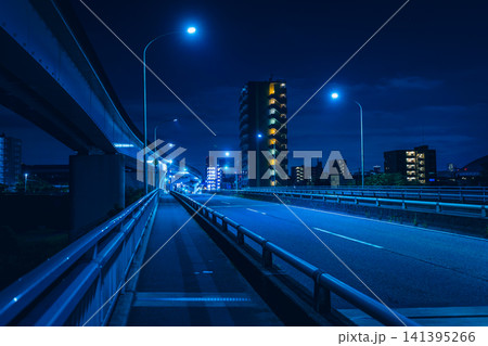 青い光に包まれた夜の橋と高架橋、遠くに輝くマンション群の都市風景 青い光に包まれた夜の橋と高架橋、遠くに輝くマンション群の都市風景 141395266