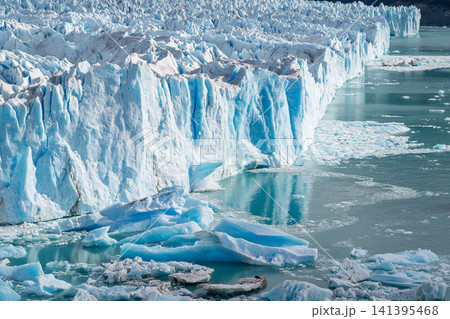 Perito moreno glacier wall shows climate change impact with melancholic feeling as majestic ice structure melts into water revealing environmental crisis through powerful natural landscape scenery Perito moreno glacier wall shows climate change impact with melancholic feeling as majestic ice structure melts into water revealing environmental crisis through powerful natural landscape scenery 141395468