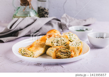 Delicious grilled rolls with cottage cheese, cheese and herbs on a plate on the table Delicious grilled rolls with cottage cheese, cheese and herbs on a plate on the table 141395657