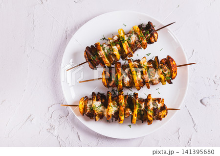 Close up of meat and potatoes baked on skewers in an air fryer on a plate on the table top view Close up of meat and potatoes baked on skewers in an air fryer on a plate on the table top view 141395680