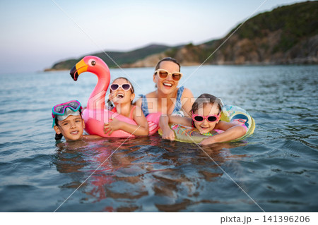 Family enjoying summer vacation swimming in ocean with inflatables Family enjoying summer vacation swimming in ocean with inflatables 141396206
