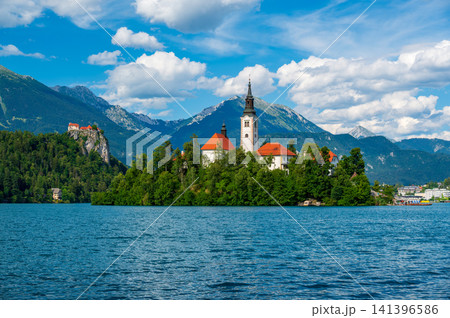 Scenic view of Lake Bled in Slovenia with turquoise water, the iconic Church of the Assumption on Bled Island, surrounded by forests and the majestic Julian Alps. Scenic view of Lake Bled in Slovenia with turquoise water, the iconic Church of the Assumption on Bled Island, surrounded by forests and the majestic Julian Alps. 141396586