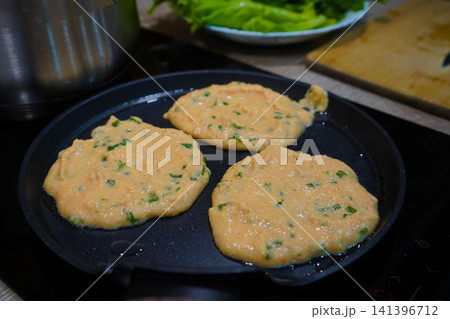 Close up of healthy fritters cooking on modern induction stove inside kitchen Close up of healthy fritters cooking on modern induction stove inside kitchen 141396712