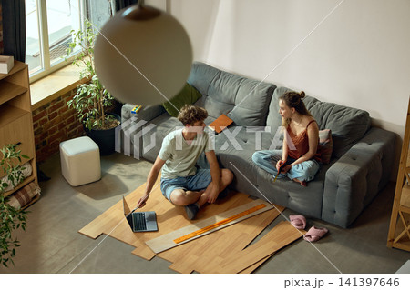 Young couple measuring flooring samples in new apartment 141397646