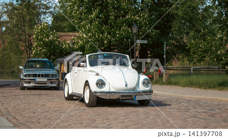 White Volkswagen Beetle Convertible Driving at Classic Car Event White Volkswagen Beetle Convertible Driving at Classic Car Event 141397708