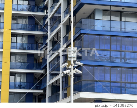 Modern blue and yellow exterior of residential building with glass windows and multiple balconies 141398276