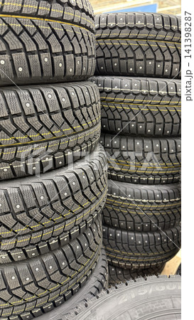 Stacked winter tires with metal studs displayed in vertical format for automotive background Stacked winter tires with metal studs displayed in vertical format for automotive background 141398287