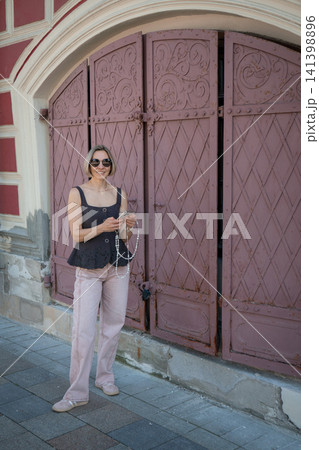 Full length portrait of woman beside ornate historic red gates in old Moscow street. Fashion, urban lifestyle, heritage architecture, travel, summer, confidence, tourism Full length portrait of woman beside ornate historic red gates in old Moscow street. Fashion, urban lifestyle, heritage architecture, travel, summer, confidence, tourism 141398896