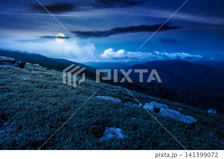 nature scenery with mountain under summer sky at night. full moon over alpine landscape of carpathian mountain with grassy slopes. low fluffy clouds on high altitude. mysterious summer vacations nature scenery with mountain under summer sky at night. full moon over alpine landscape of carpathian mountain with grassy slopes. low fluffy clouds on high altitude. mysterious summer vacations 141399072