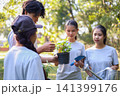 Young adults volunteer planting trees in the park for environmental conservation and sustainable future. Community service, reforestation, nature care and teamwork concept. 141399176