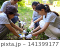 Young adults volunteer planting trees in the park for environmental conservation and sustainable future. Community service, reforestation, nature care and teamwork concept. 141399177