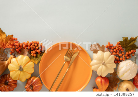 Autumn table setting with orange plate and pumpkins on blue background 141399257