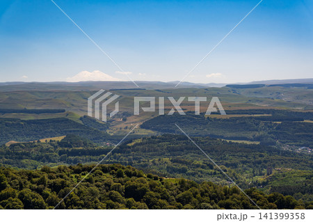 Panoramic view of the green valley and the snowy peak of Mount Elbrus on the horizon against the blue sky on a sunny clear morning in Kislovodsk Stavropol territory, Russia 141399358