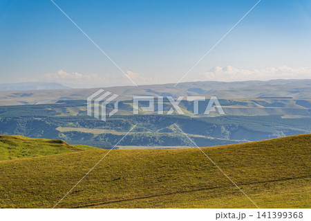 Panoramic view of the green valley and the snowy peak of Mount Elbrus on the horizon against the blue sky on a sunny clear morning in Kislovodsk Stavropol territory, Russia Panoramic view of the green valley and the snowy peak of Mount Elbrus on the horizon against the blue sky on a sunny clear morning in Kislovodsk Stavropol territory, Russia 141399368