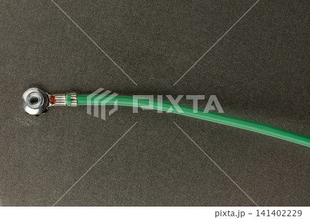 Green cable connected to a metal fitting on a dark surface 141402229