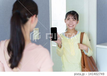パーソナルジムで入店前にスマートフォンを見せる女性 141402749