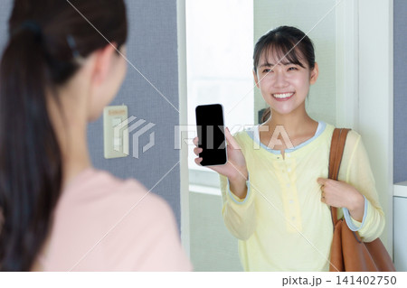 パーソナルジムで入店前にスマートフォンを見せる女性 パーソナルジムで入店前にスマートフォンを見せる女性 141402750