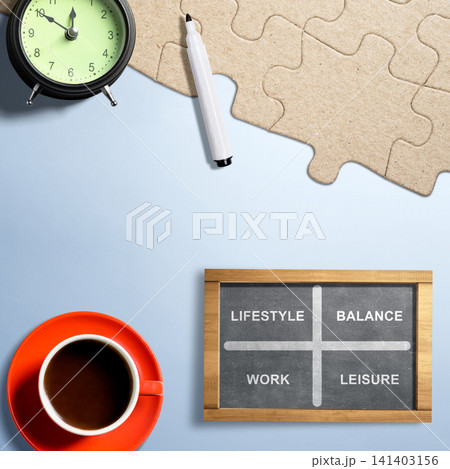 Flat lay of a chalkboard with work-life balance quadrants, set alongside a coffee cup, alarm clock, marker, and puzzle pieces on a blue background Flat lay of a chalkboard with work-life balance quadrants, set alongside a coffee cup, alarm clock, marker, and puzzle pieces on a blue background 141403156
