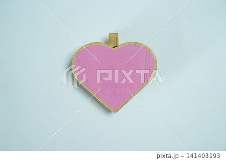 A minimalist flat lay photo of a single pink wooden heart-shaped clothespin clip centered on a textured light blue background. Great for love, Valentine's, or romantic concepts A minimalist flat lay photo of a single pink wooden heart-shaped clothespin clip centered on a textured light blue background. Great for love, Valentine's, or romantic concepts 141403193