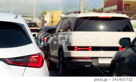 Rear view of modern cars stopped in a heavy traffic congestion during the daytime. Scene captures the bright red tail lights and sleek automotive designs queued up on a city road at Thailand. Rear view of modern cars stopped in a heavy traffic congestion during the daytime. Scene captures the bright red tail lights and sleek automotive designs queued up on a city road at Thailand. 141403732