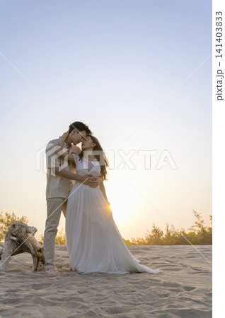 A happy Indonesian southeast asian couple in wedding attire poses together on a sandy beach during a warm golden hour sunset A happy Indonesian southeast asian couple in wedding attire poses together on a sandy beach during a warm golden hour sunset 141403833