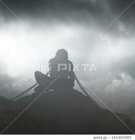 A conceptual silhouette of a man sitting bound in heavy chains on a rocky hill under a dark, stormy, and misty sky, symbolizing depression, addiction, captivity, and mental struggles A conceptual silhouette of a man sitting bound in heavy chains on a rocky hill under a dark, stormy, and misty sky, symbolizing depression, addiction, captivity, and mental struggles 141403905